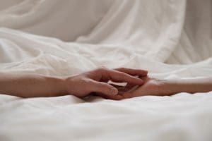 holding hands against white sheets